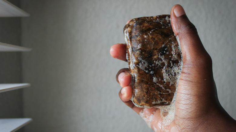 Hand holding bar of black soap