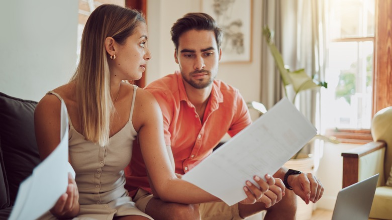 Unhappy couple sat on sofa paperwork