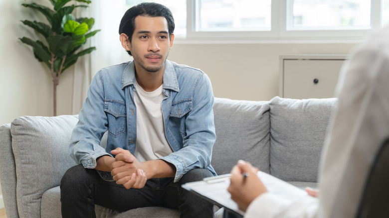 Man sitting on a couch with a therapist taking notes