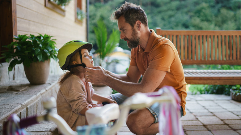 Dad putting bike helmet on daughter