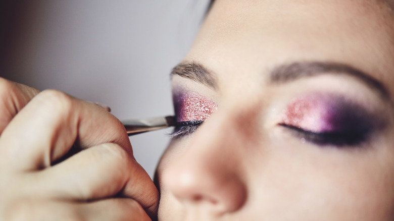 Makeup artist applying glitter eyeshadow 