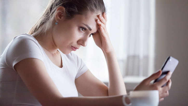 Stressed woman looking at phone