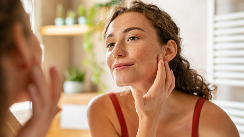 Woman looking at skin in mirror