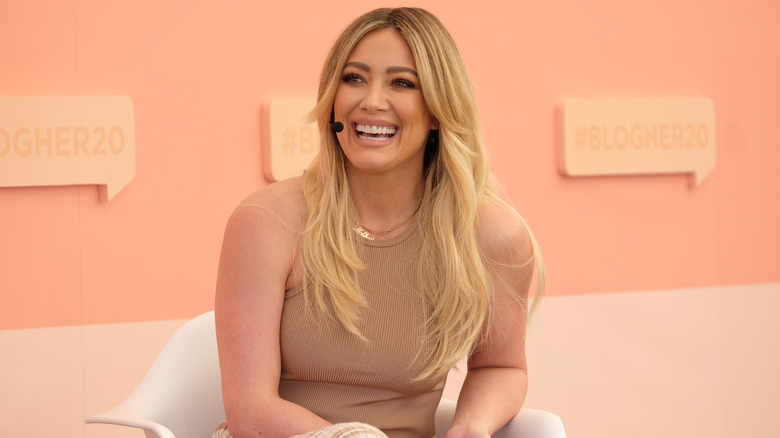 Hilary Duff laughing while wearing an earpiece mic