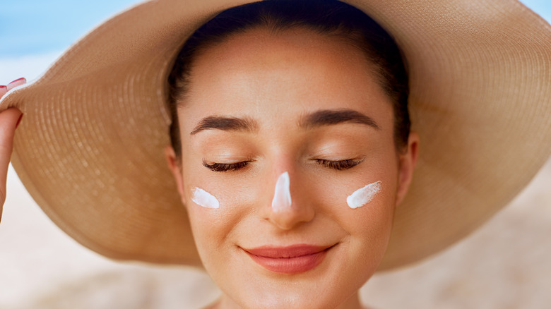 A woman wearing a sunhat and sunscreen on her face 