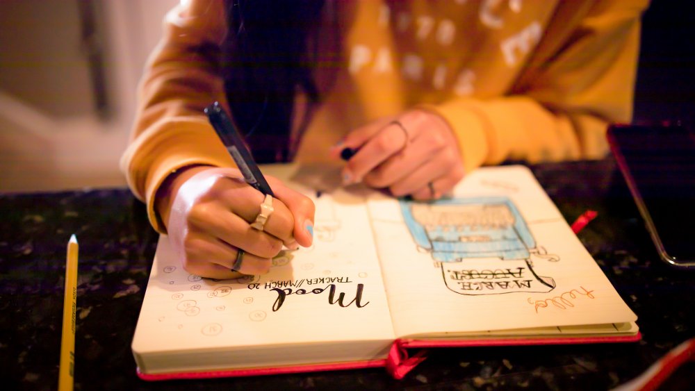 woman's hand writing notes in her journal 