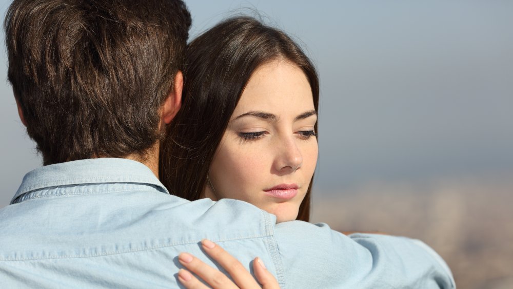 Doubtful woman hugging boyfriend