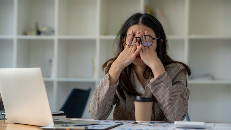 An exhausted woman in front of a laptop