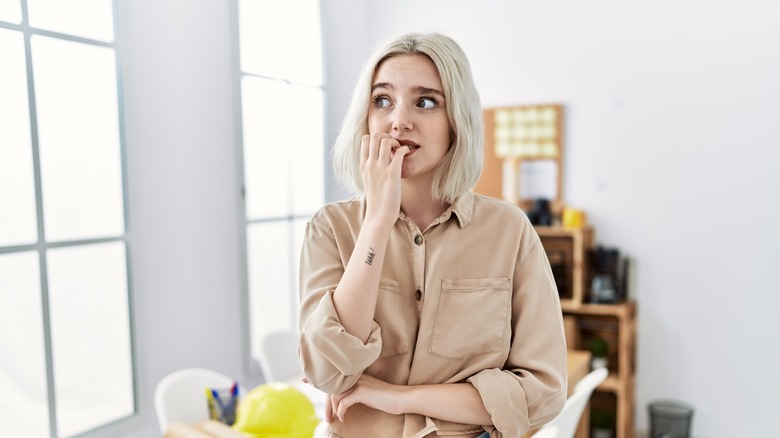 an anxious woman chewing on fingernails