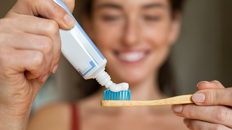 Woman applying toothpaste to brush 