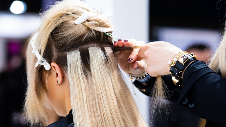 Woman getting hair extensions put in 