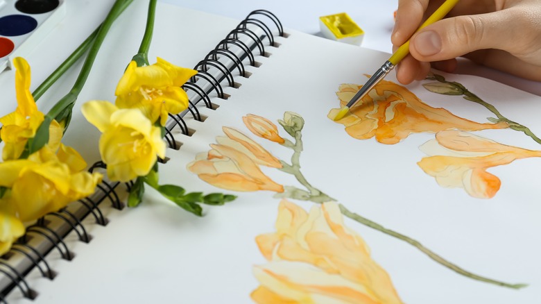 Hand painting yellow flowers on sketchpad