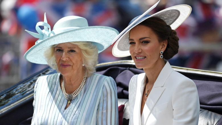 Queen Camilla & Princess Catherine smiling in carriage wearing hats