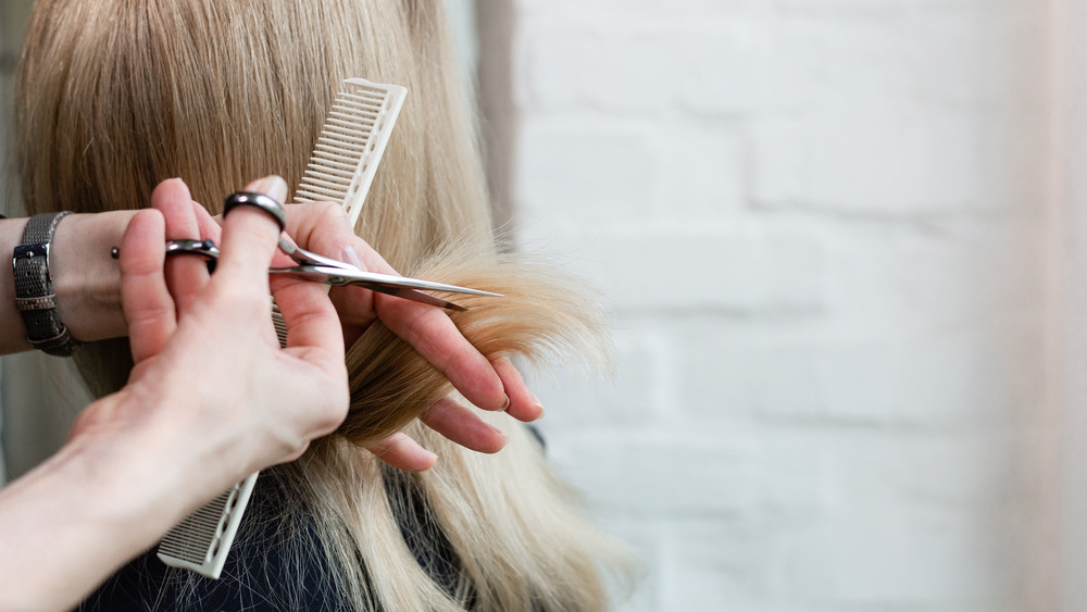 Hands using a comb and scissors to cut hair 