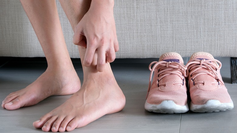 Woman itching her ankle next to running shows 