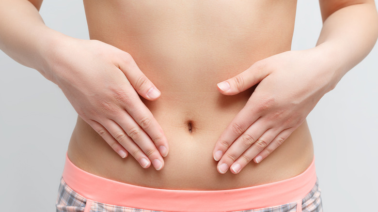 A lady pointing towards her belly button area