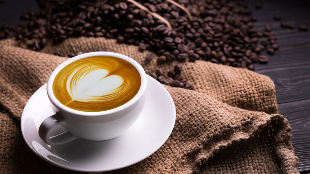 Mug of coffee with coffee beans next to it