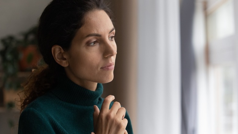 Pensive woman looks out window