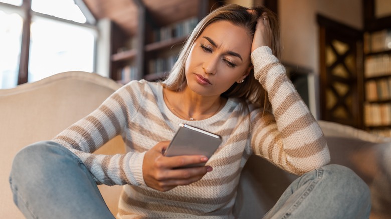 Woman looking at phone anxiously 