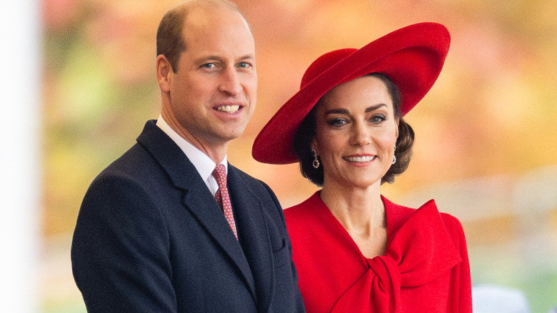 Kate Middleton in red dress and hat beside Prince William