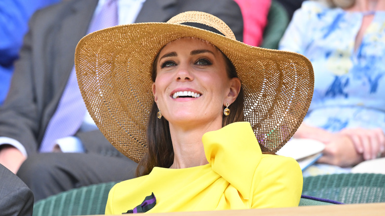 Kate Middleton smiling in yellow dress and wide hat at Wimbledon