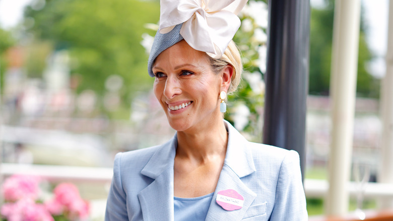 Zara Tindall smiling in a blue pastel outfit and white fascinator