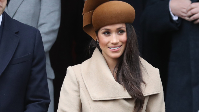 Meghan Markle wearing a beige coat and brown hat