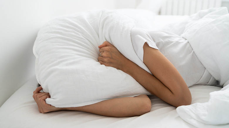 Person covering head with pillow
