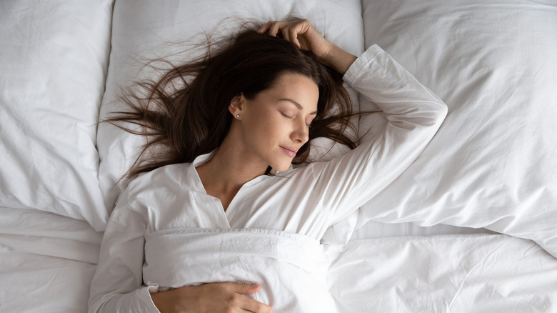 A woman sleeping in white bedding 
