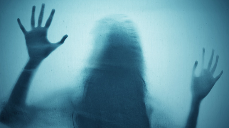 Woman hiding behind matte glass scary