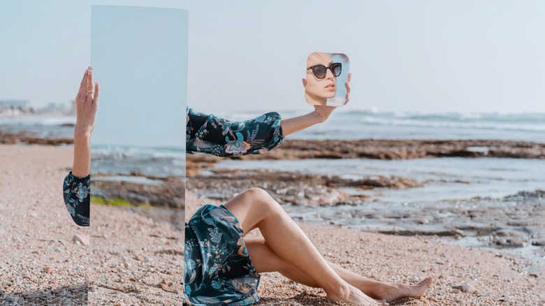 woman holding mirrors on beach