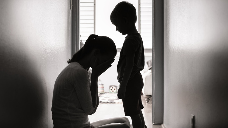 woman covering face next to little boy