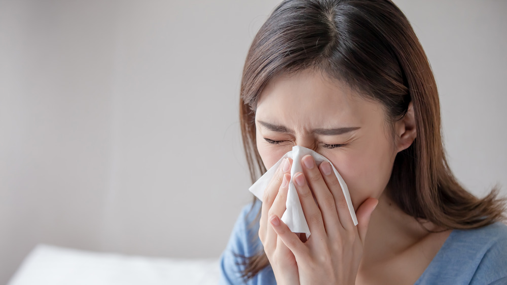 Woman blowing nose into tissue