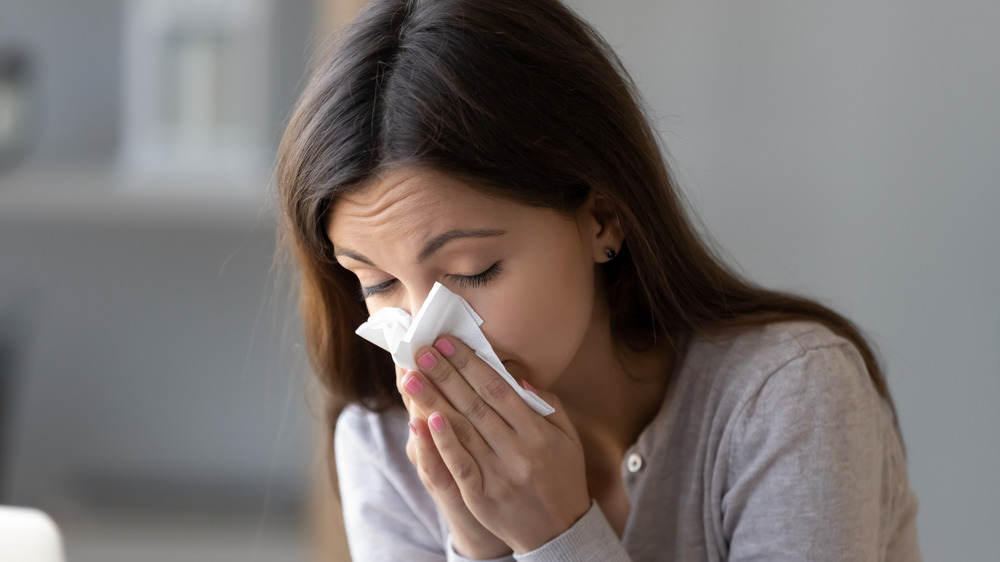 woman holding tissue to nose