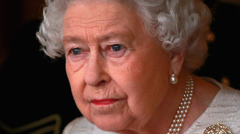 Queen Elizabeth looking out window at Buckingham