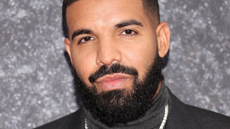 Rapper Drake looks at the camera as he poses against a grey backdrop