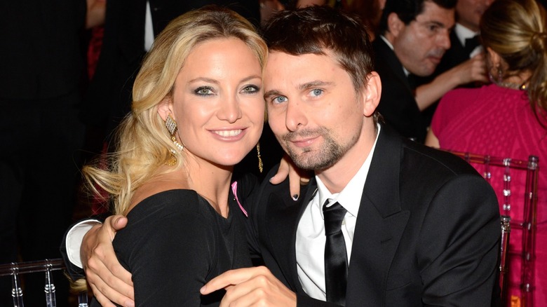 Kate Hudson and Matt Bellamy sitting at a table posing cheek to cheek
