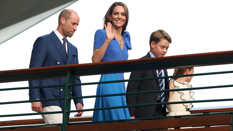 Kate Middleton smiling and waving while walking with Prince William and their children