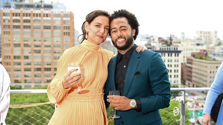 Katie Holmes and Bobby Wooten III stand arm-in-arm on a balcony