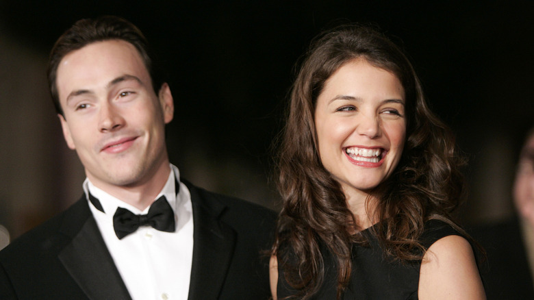 Chris Klein and Katie Holmes smiling while walking a red carpet.