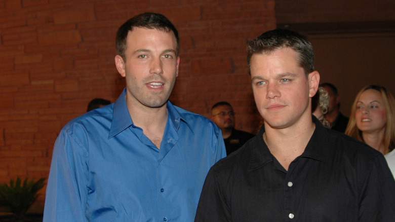Ben Affleck in a blue shirt beside Matt Damon in a black shirt