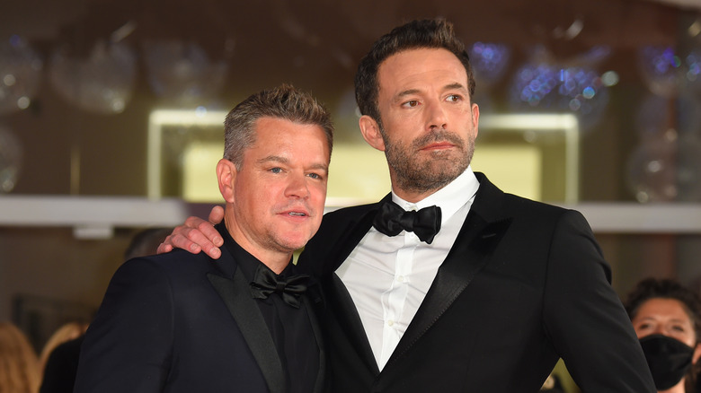 Ben Affleck with arm around Matt Damon and both in formals