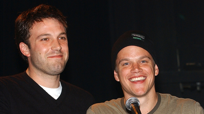 Matt Damon in a beanie beside Ben Affleck in a black V-neck sweater