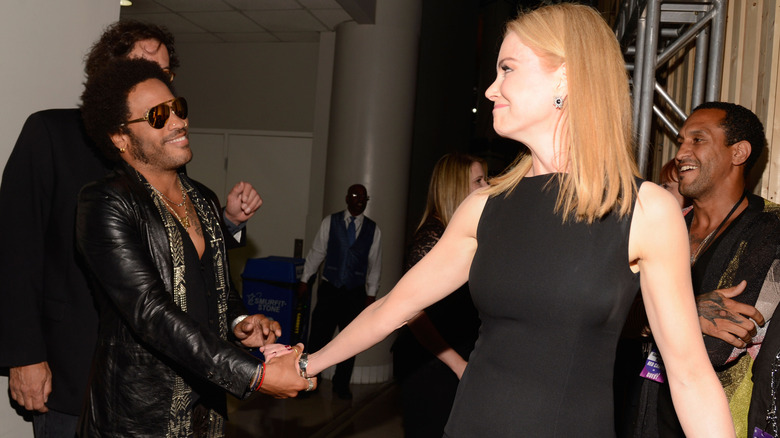 Lenny Kravitz and Nicole Kidman smiling and greeting one another at an event