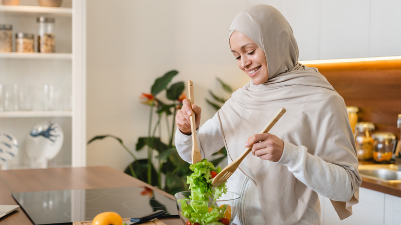 Vegan woman making a salad with greens 