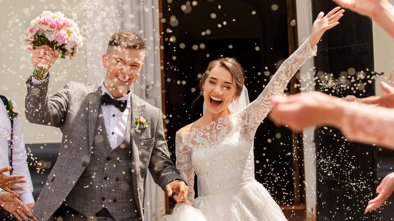 Bride and groom exit their ceremony as rice is thrown