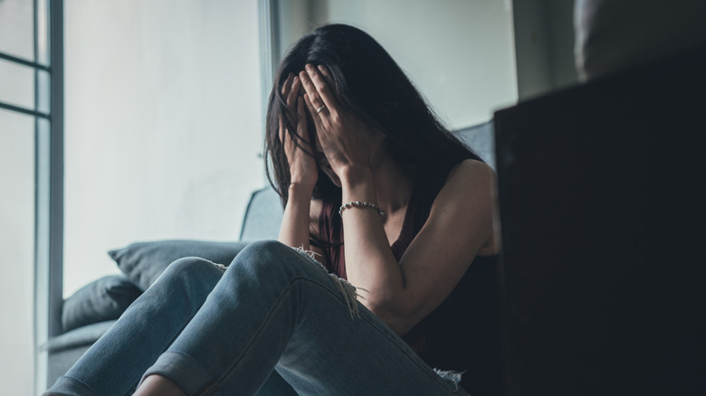 Woman on floor with head in hands