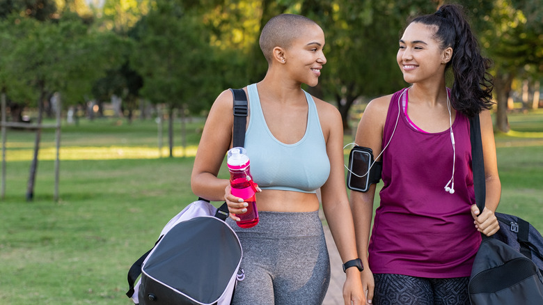 women in athletic clothes smile while walking 