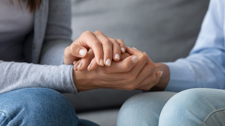 two people sitting close-up on hand holding