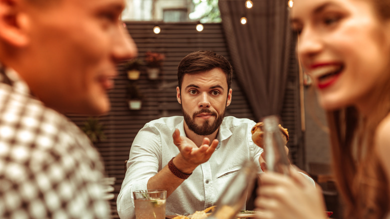 Confused man sitting across from couple